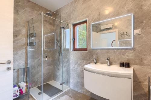 een badkamer met douche, wastafel en spiegel bij Casa Anka in Medulin