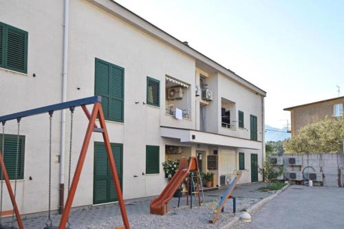 a building with green shuttered windows and a playground at Apartment Leo in Ploče