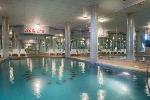 a swimming pool in a building with tables and chairs at Queens Hotel & Spa in Brighton & Hove