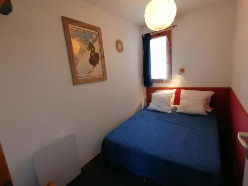 - une petite chambre avec un lit bleu et une fenêtre dans l'établissement Appartement 4 pers · Ski aux pieds · Balcon · Casier à skis · Parking gratuit - FR-1-181-2534, à Aime La Plagne