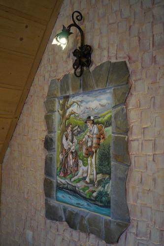 a mural on a brick wall with a painting on it at Willa Tatrzański Zomecek in Kościelisko