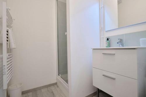 une salle de bain blanche avec un lavabo et un miroir dans l'établissement Le Nid Douillet - Appart 2-4P vieux Boulogne, à Boulogne-sur-Mer