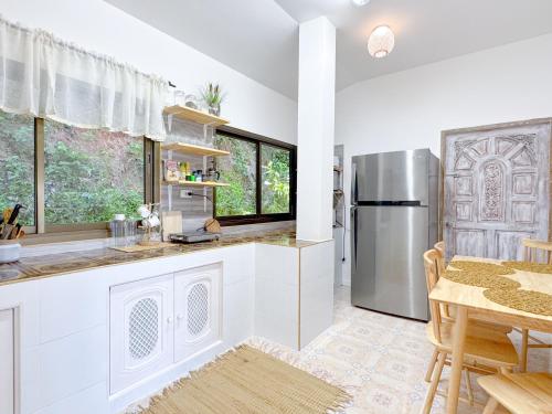 a kitchen with a stainless steel refrigerator and a table at Sea Dreamer Ao Yon Beach House in Ban Ao Makham