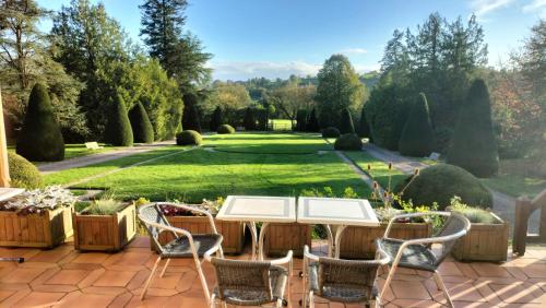 a patio with a table and chairs and a garden at Domaine des Thomins in Cisai-Saint-Aubin