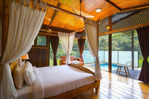 a bedroom with a bed with curtains and a pool at The Arboreal Resort in Āmbavna