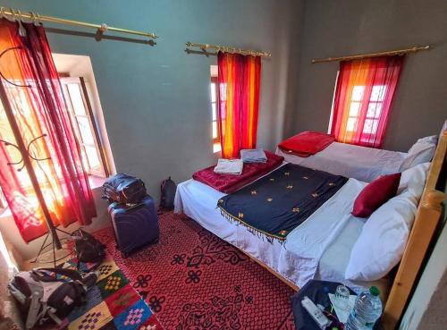 a bedroom with two beds and luggage and windows at Maggaman Guest House in Tafraoute Sidi Ali