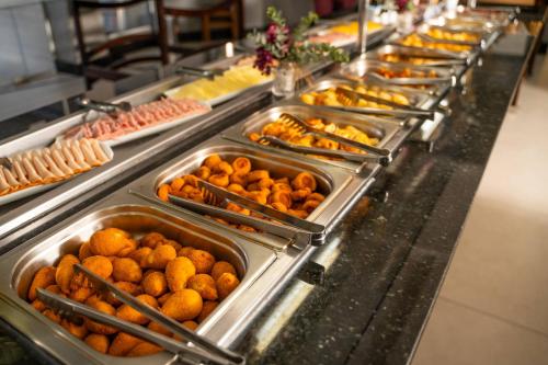a buffet line with many trays of food at Boulevard Beach Canasvieiras Hotel in Florianópolis
