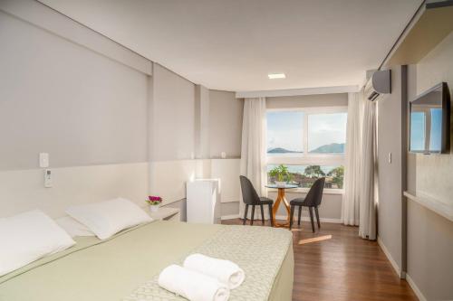 a hotel room with a bed and a table and chairs at Boulevard Beach Canasvieiras Hotel in Florianópolis