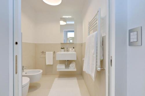 a white bathroom with a sink and a toilet at Portopiccolo Apartments in Sistiana