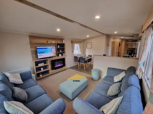 a living room with a blue couch and a tv at Golden Palm Resort - The Adelaide - Coastal Caravan Breaks in Skegness