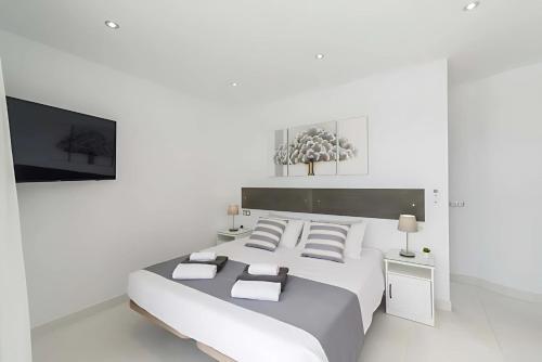 a white bedroom with a large bed and a tv at Villa Bella Valen in Playa Blanca