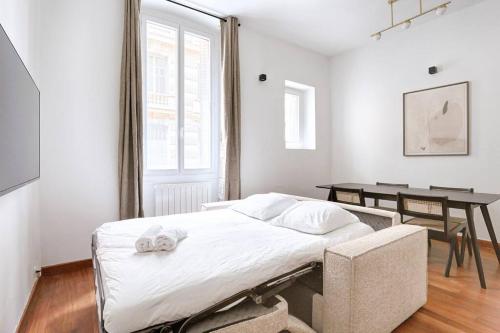 une chambre blanche avec un lit et une table dans l'établissement Concorde Saint Honore Apartment 1BR 4P, à Paris