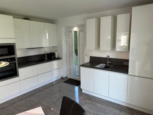 a kitchen with white cabinets and black counter tops at Ferienwohnung Forstblick in Kranenburg