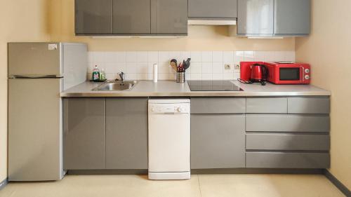Il comprend une petite cuisine équipée d'un évier et d'un four micro-ondes rouge. dans l'établissement Cosy'Appart - LE MARTEL, à Rouen