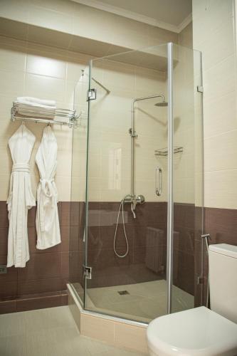 a bathroom with a shower with a toilet and a robe at Casablanca Apart Hotel in Bishkek