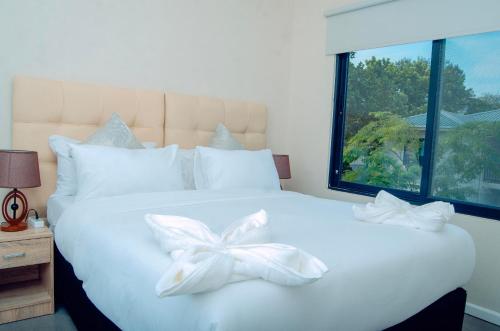 - un lit blanc avec une archet blanche dans l'établissement Estate Apartments, à Lusaka