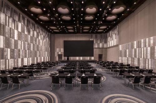 a large room with tables and chairs and a screen at W Bangkok Hotel in Bangkok