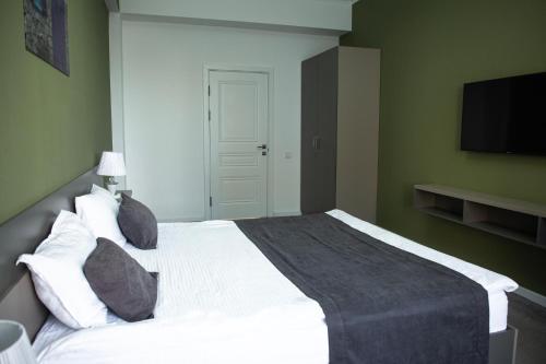 a bedroom with a white bed and a flat screen tv at Casablanca Apart Hotel in Bishkek