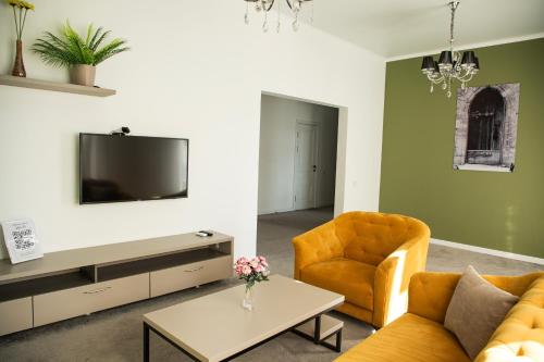 a living room with a couch and a chair and a tv at Casablanca Apart Hotel in Bishkek