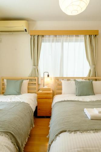 a bedroom with two beds and a window at Beyond Comfort 新宿大久保 - 最大10名でゆったり滞在 in Tokyo