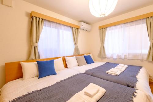 two beds in a room with windows at Beyond Comfort 新宿大久保 - 最大10名でゆったり滞在 in Tokyo