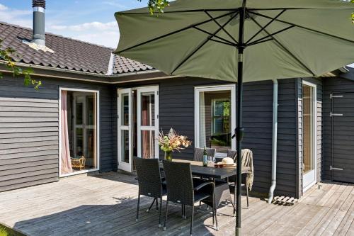 a patio with a table with a green umbrella at Beautiful Holiday Home In Mols Close To The Water in Knebel