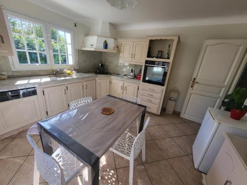 a kitchen with white cabinets and a table and chairs at Chambre ERREGUINA in Hasparren