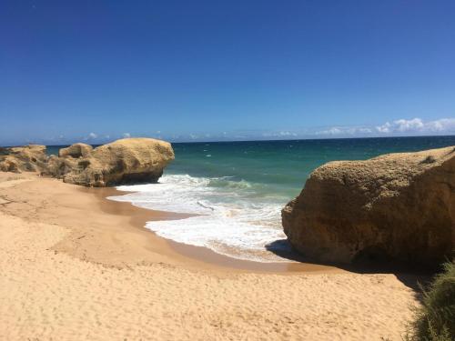 a beach with two large rocks and the ocean at Casa Saudade luxury rooms in Faro