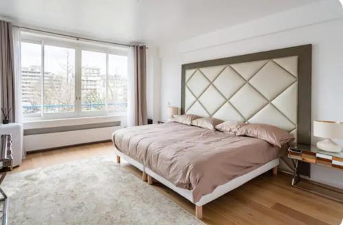 une chambre avec un grand lit et une grande fenêtre dans l'établissement 2 bedroom appartement champs Élysée, à Paris