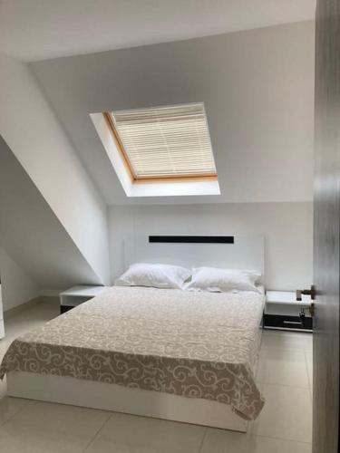 a white bedroom with a bed with a skylight at Апартамент Пирин in Sandanski