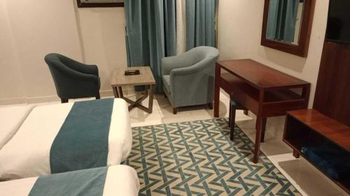a hotel room with a bed and a desk and chairs at Etlalat Obhur in Jeddah