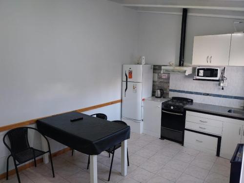cocina con mesa, fogones y nevera en La casita, en El Calafate
