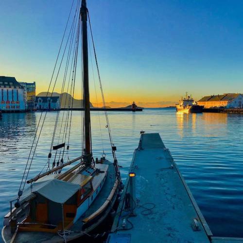 a boat docked in the water at a dock at Hellegata 5 - in the heart of Ålesund in Ålesund