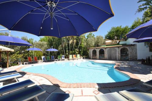 a large pool with blue umbrellas and chairs at Villa Eva in Anacapri