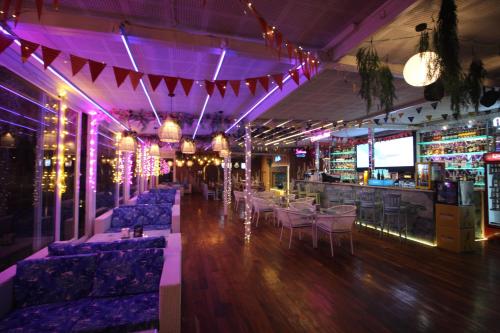 a bar with purple lighting and couches in a room at Moksha Riverside Resort in Kasol