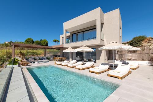 a house with a swimming pool with chairs and umbrellas at Mirena Luxury Living-Mirena Villa in Afantou