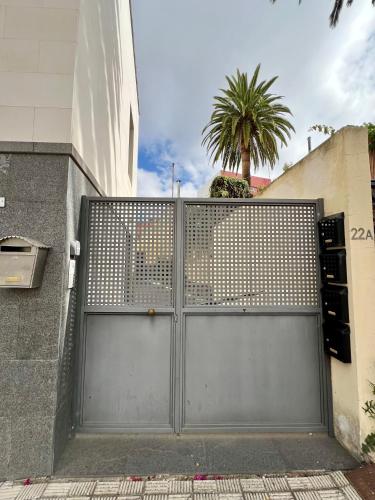 a metal gate in front of a building with a palm tree at Detail Tacoronte in Tacoronte
