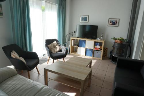 a living room with a couch and chairs and a tv at Kustverhuur, Vakantiepark Fort Soleil 52 in Breskens