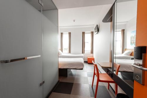 a room with two beds and a table and a mirror at easyHotel Amsterdam Arena Boulevard in Amsterdam