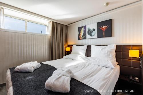 a bedroom with a large bed with white sheets and pillows at Hotelship KD Moment Köln in Cologne