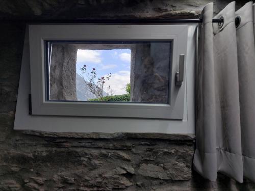 a window in a stone wall with a view at Le Glacier in La Salle