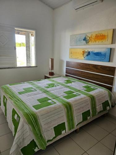 a bedroom with a bed with a green and white quilt at Casa de Paraia em Aracaju in Aracaju
