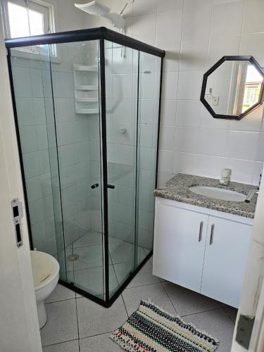 a bathroom with a glass shower with a toilet and a sink at Casa de Paraia em Aracaju in Aracaju