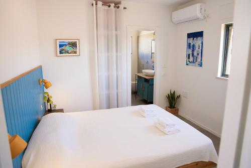 a bedroom with a white bed and a bathroom at Mitzpe Ramon Desert Escape in Mitzpe Ramon