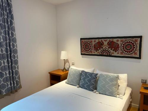 a bedroom with a white bed with blue pillows at Art House in Luanda