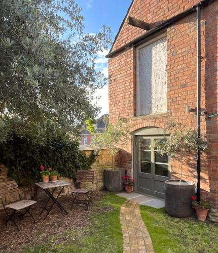 a brick house with a table and chairs in the yard at Victorian Red Brick Barn in the Heart of Stamford in Lincolnshire
