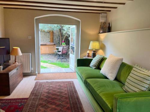 a living room with a green couch and a sliding glass door at Victorian Red Brick Barn in the Heart of Stamford in Lincolnshire