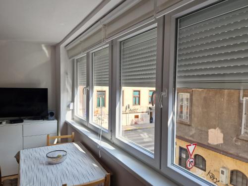 Zimmer mit einem Tisch und einem Fenster mit Jalousien in der Unterkunft Cheyf Modern Studio in Center in Sarajevo