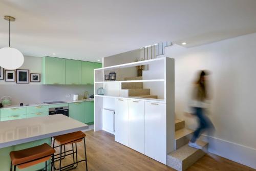 a woman walking through a kitchen with green cabinets at Feel Discovery Casa de Cima Douro Valley in Riba Douro