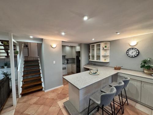 a kitchen with a counter with chairs and a clock at Olives by Agnes in Hartbeespoort